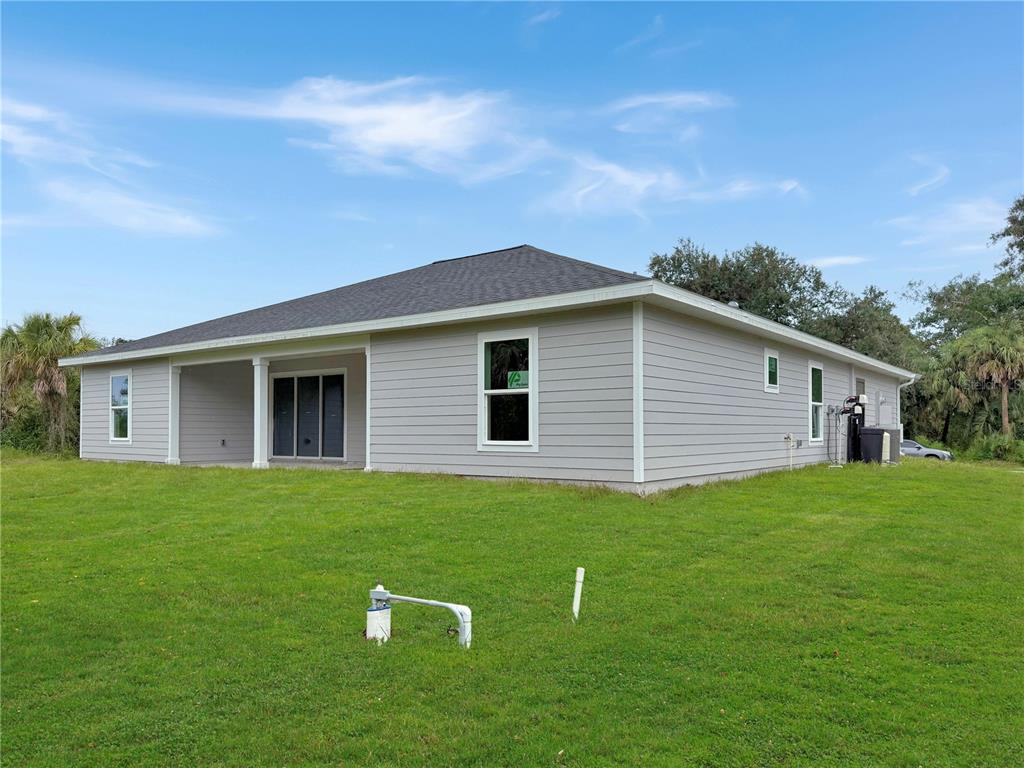 The exterior of a light gray, single-story house with a covered patio and grassy yard — 16419 STRAUSS AVENUE, PORT CHARLOTTE, FL