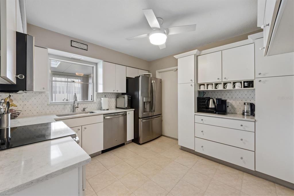 A kitchen with white cabinets, stainless steel appliances, a ceiling fan, and tile flooring — 3512 21ST AVENUE W, BRADENTON, FL