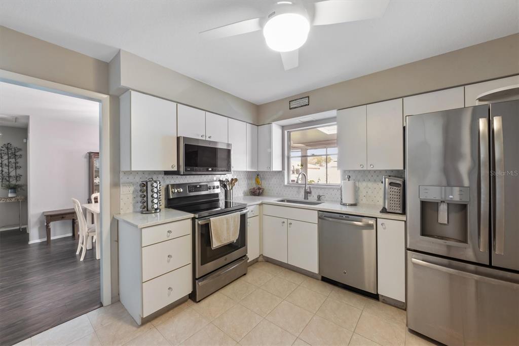 A kitchen with white cabinets, stainless steel appliances, and light-colored tile flooring — 3512 21ST AVENUE W, BRADENTON, FL