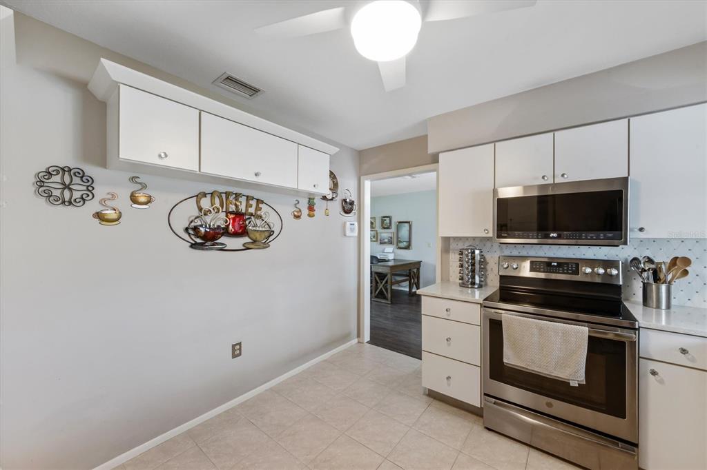 A kitchen features white cabinets, stainless steel appliances, and coffee-themed wall decor — 3512 21ST AVENUE W, BRADENTON, FL