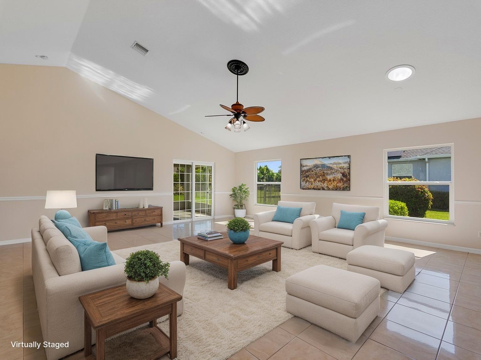 A living room with vaulted ceilings, tile floors, a ceiling fan, and beige furniture — 8340 Paladin Square, Vero Beach FL 32967, VERO BEACH, FL