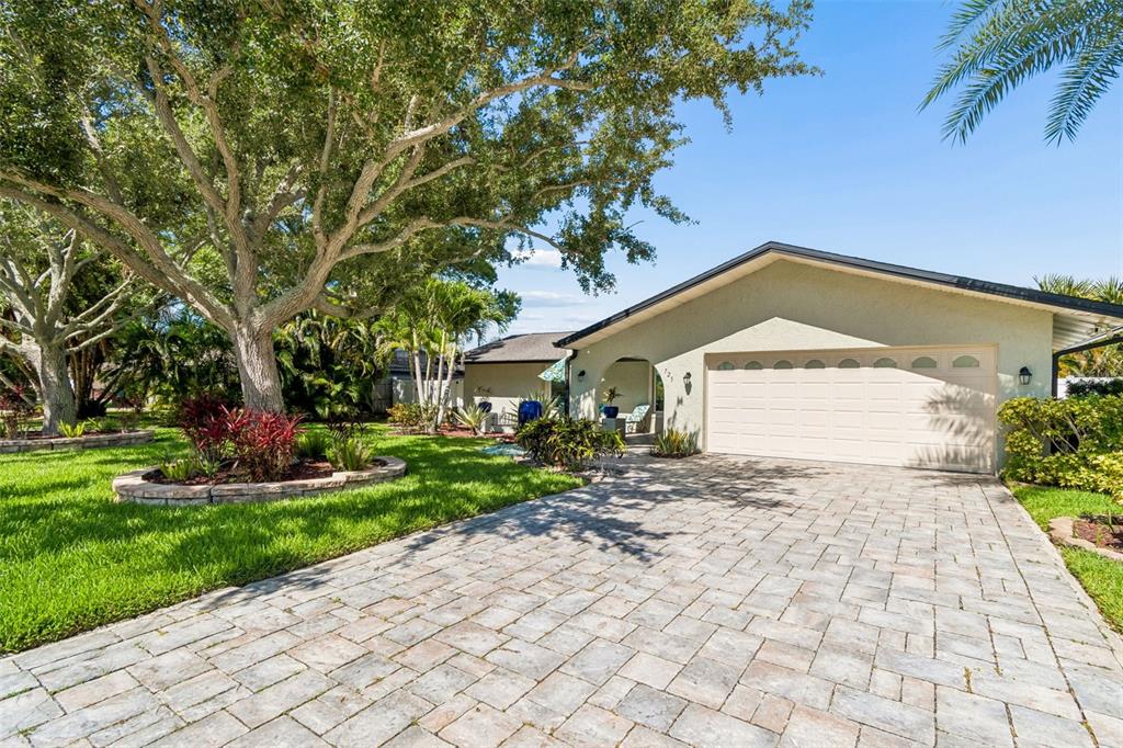 A single-story house with a paved driveway, a two-car garage, and a large shade tree — 725 DEL ORO DRIVE, SAFETY HARBOR, FL