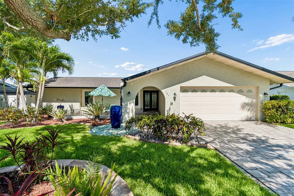 A single-story house with a beige stucco exterior, a two-car garage, and landscaped front yard — 725 DEL ORO DRIVE, SAFETY HARBOR, FL