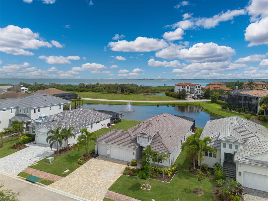 An aerial view shows several suburban houses with tiled roofs situated near a small pond — 5504 TITLE ROW DRIVE, BRADENTON, FL