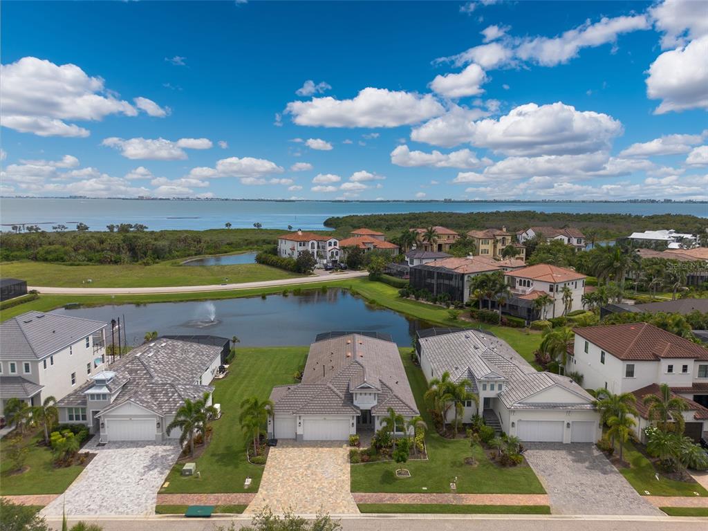 An aerial view shows three suburban houses with tiled roofs situated along a small pond — 5504 TITLE ROW DRIVE, BRADENTON, FL