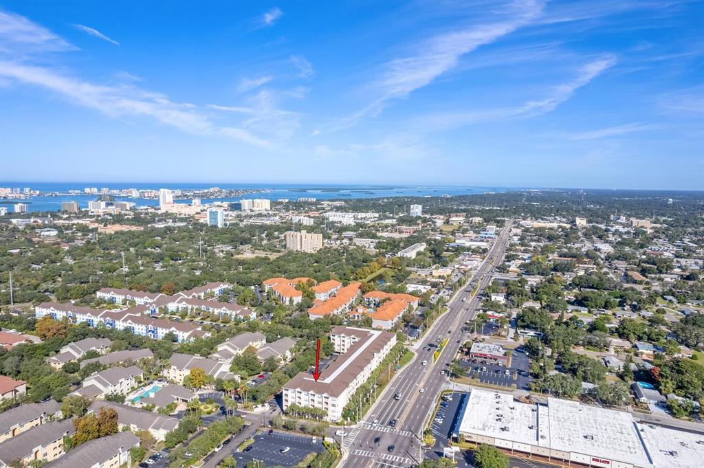 An aerial view shows a multi-story apartment building with a red arrow pointing toward it — 1216 S MISSOURI AVENUE UNIT 226, CLEARWATER, FL