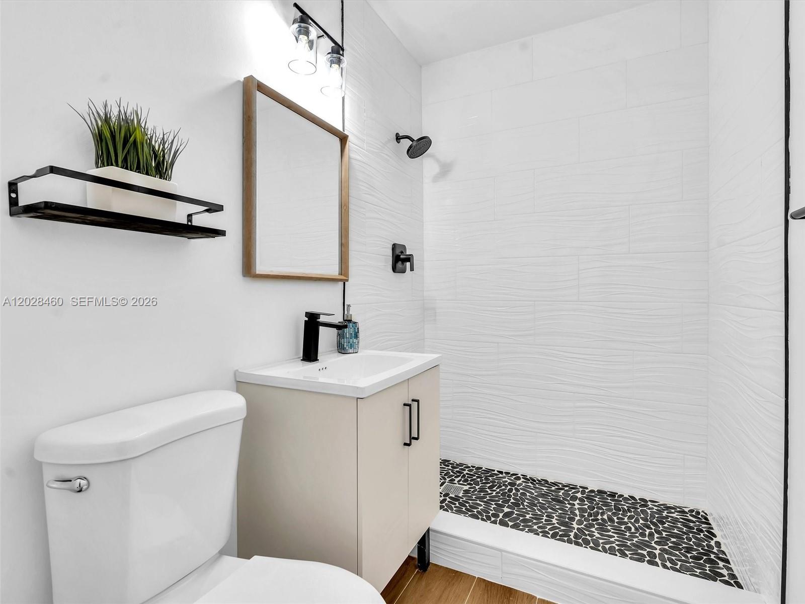 A bathroom features a vanity, toilet, and a walk-in shower with textured white tile walls — 1365 NE 130th St, North Miami FL 33161, NORTH MIAMI, FL