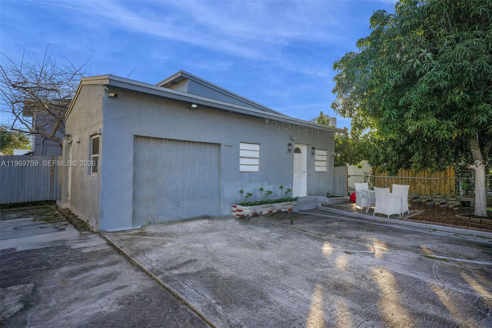 A gray, single-story building features a garage door, a front entrance, and a concrete driveway — 2104 NW 1St Ter, Miami FL 33125, MIAMI, FL
