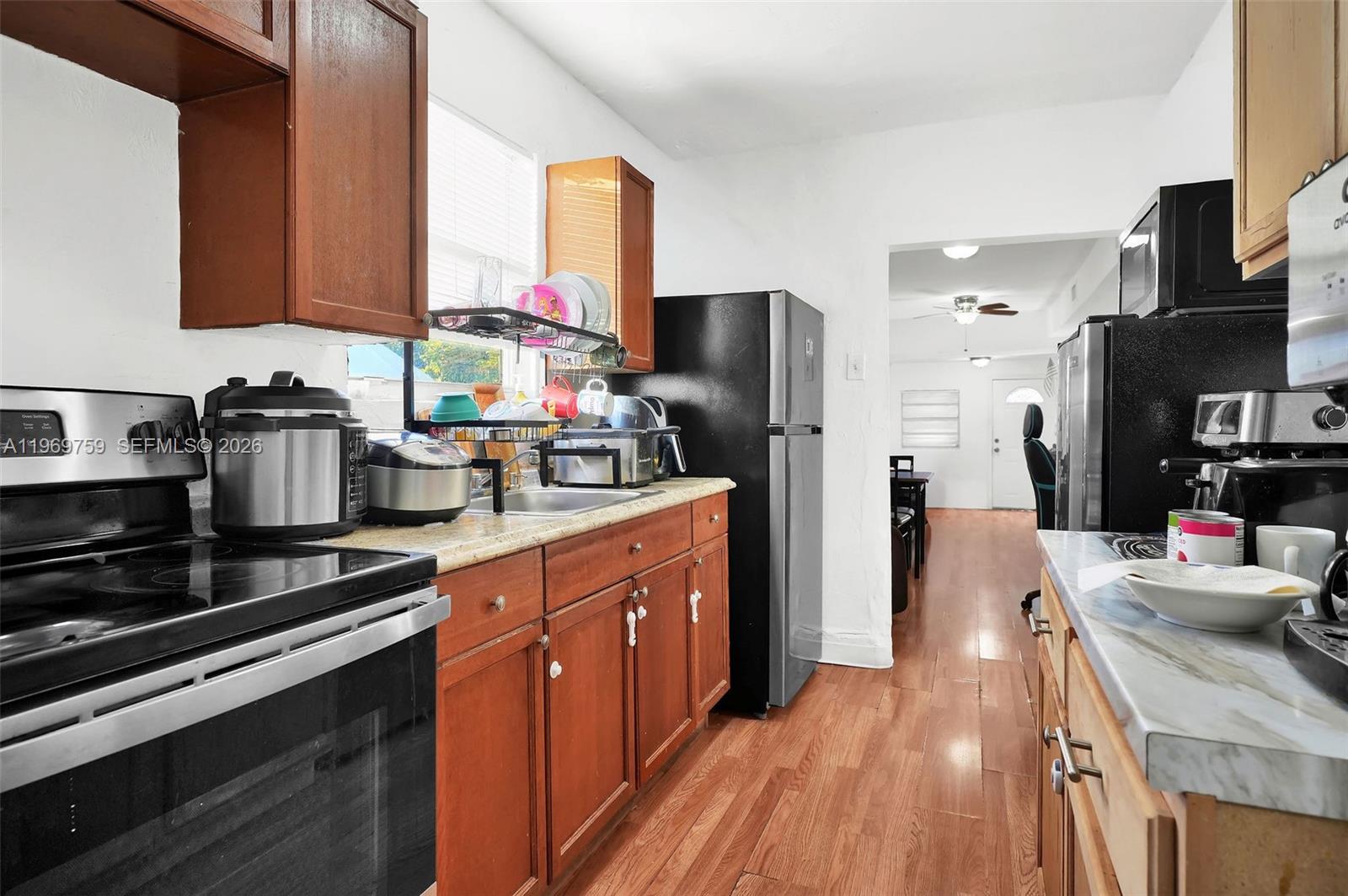 A galley-style kitchen features wood cabinets, black appliances, and light-colored countertops — 2104 NW 1St Ter, Miami FL 33125, MIAMI, FL