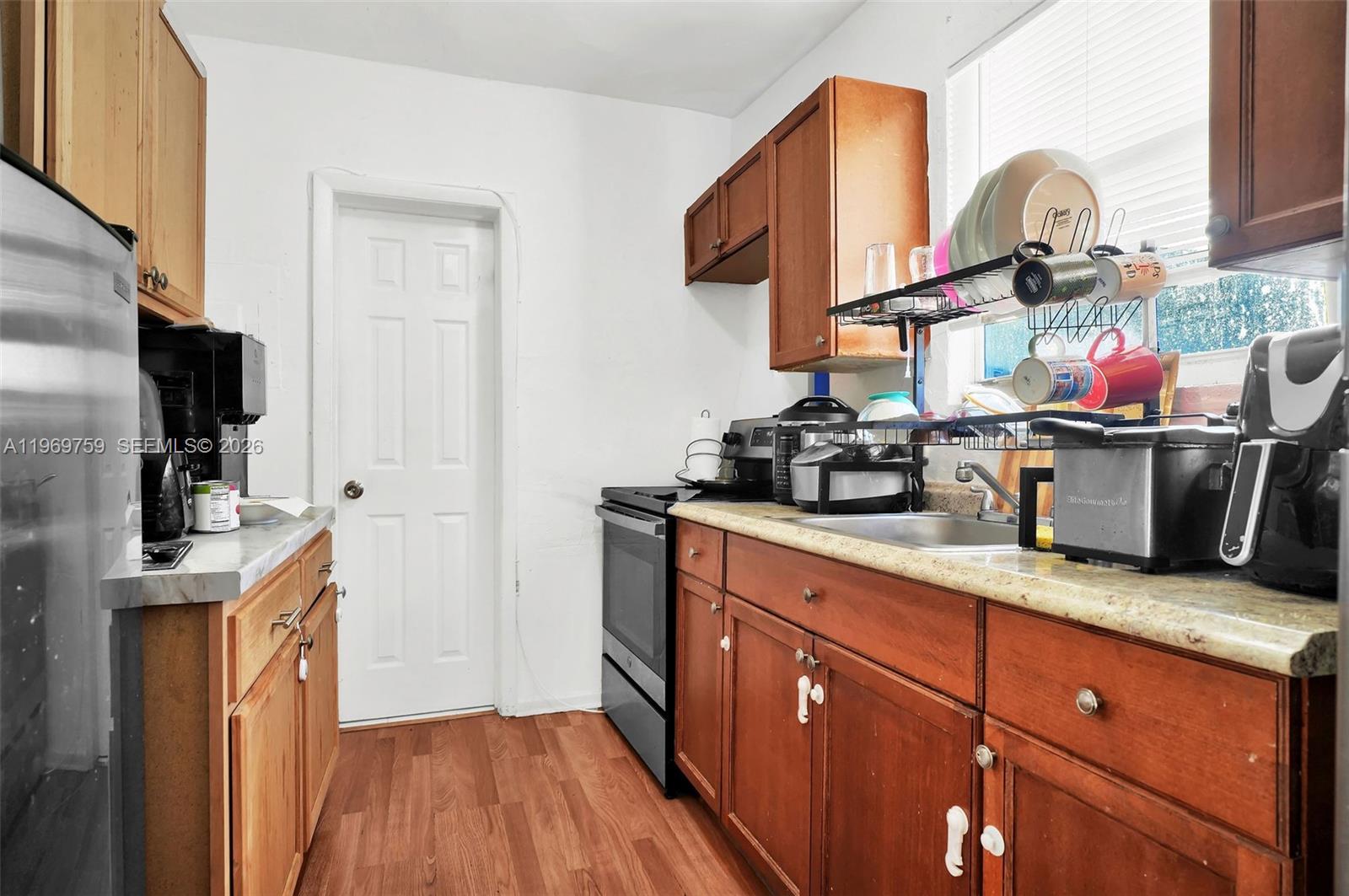A small kitchen features wooden cabinets, a stainless steel refrigerator, and a black stove — 2104 NW 1St Ter, Miami FL 33125, MIAMI, FL