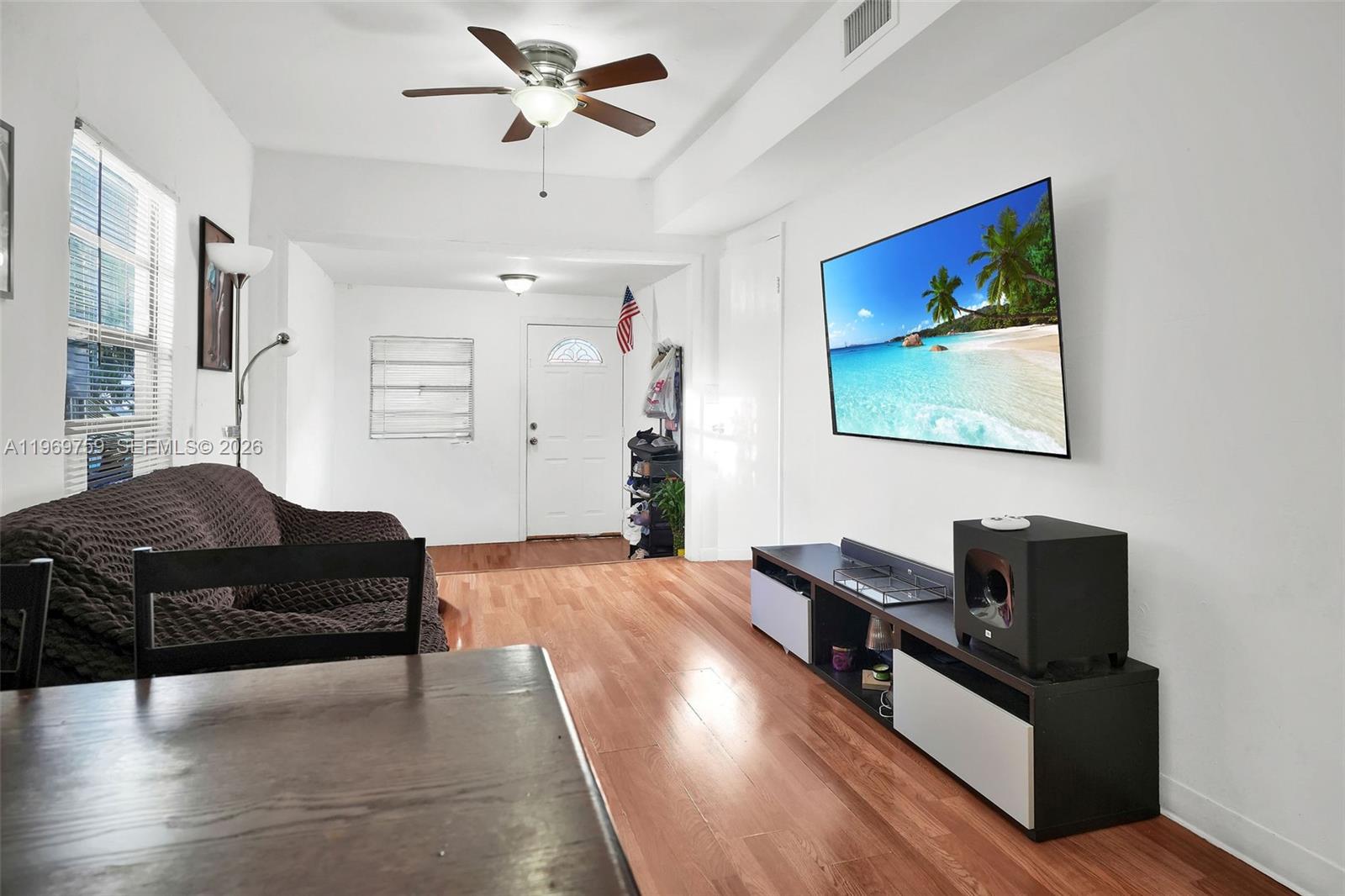 A living room features hardwood floors, a ceiling fan, a wall-mounted television, and a sofa — 2104 NW 1St Ter, Miami FL 33125, MIAMI, FL