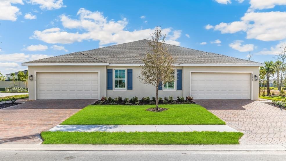 A duplex house with two garage doors, blue shutters, and a central tree in front — 16282 BRIDLE RIDGE STREET, PORT CHARLOTTE, FL