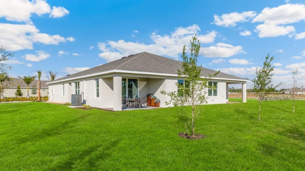 The rear exterior of a single-story house features a covered patio and a grassy yard — 16282 BRIDLE RIDGE STREET, PORT CHARLOTTE, FL