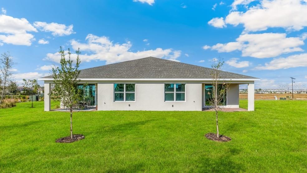 The back exterior of a single-story house features a covered patio and a grassy yard — 16282 BRIDLE RIDGE STREET, PORT CHARLOTTE, FL