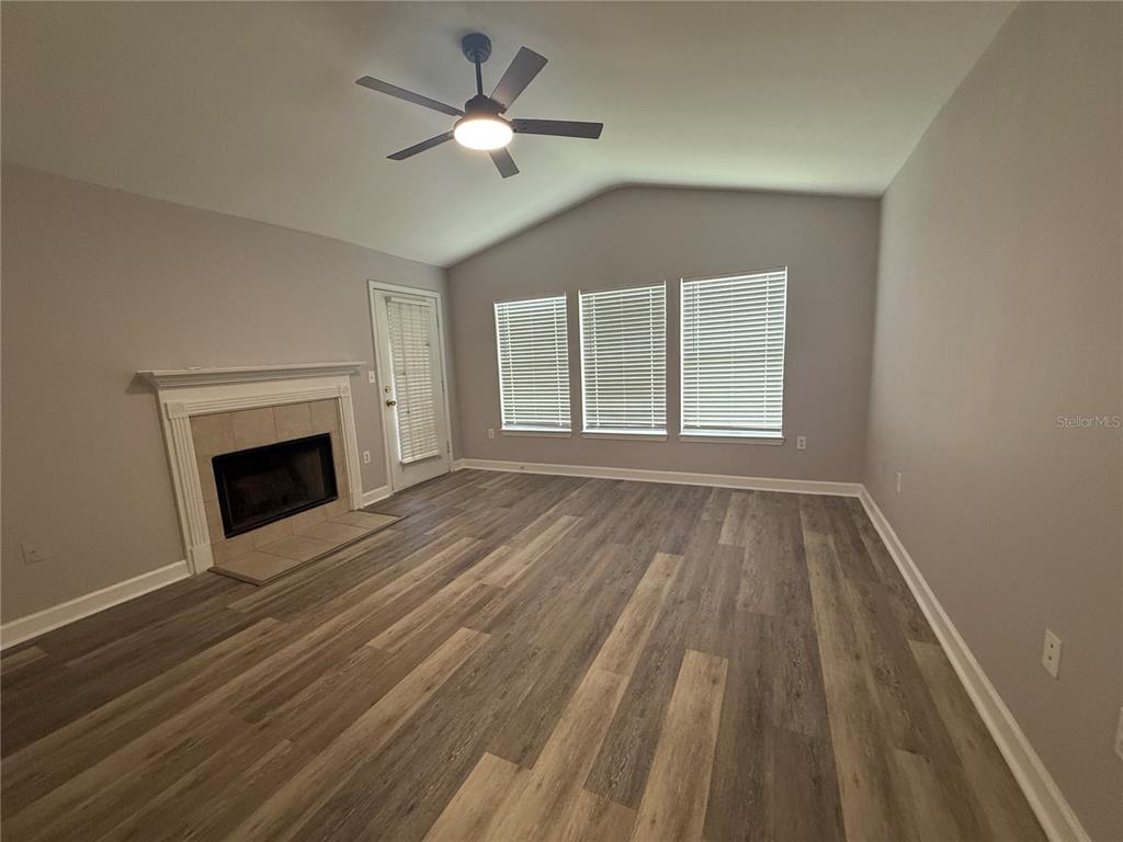 A living room features a fireplace, vaulted ceiling, ceiling fan, and wood-look flooring — 18293 BRIDLE CLUB DRIVE UNIT 18293, TAMPA, FL