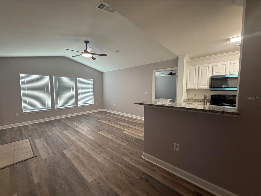 An open-concept living area features wood-look flooring, a vaulted ceiling, and a kitchen breakfast bar — 18293 BRIDLE CLUB DRIVE UNIT 18293, TAMPA, FL