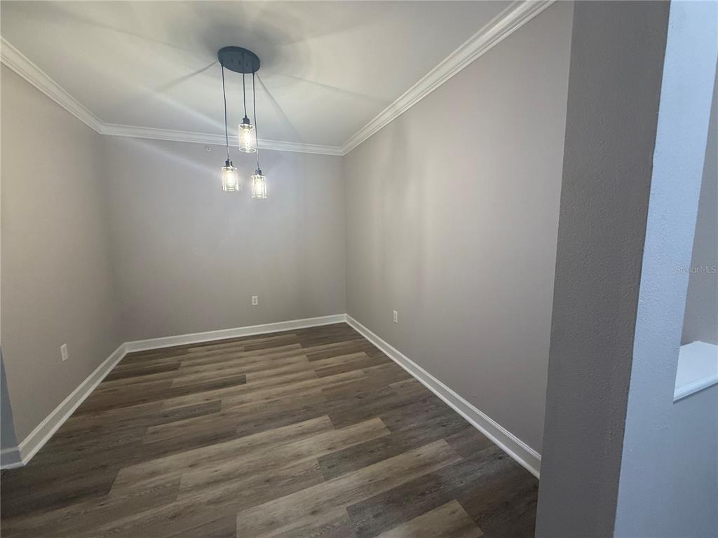 An empty dining area features light gray walls, crown molding, and wood-look plank flooring — 18293 BRIDLE CLUB DRIVE UNIT 18293, TAMPA, FL