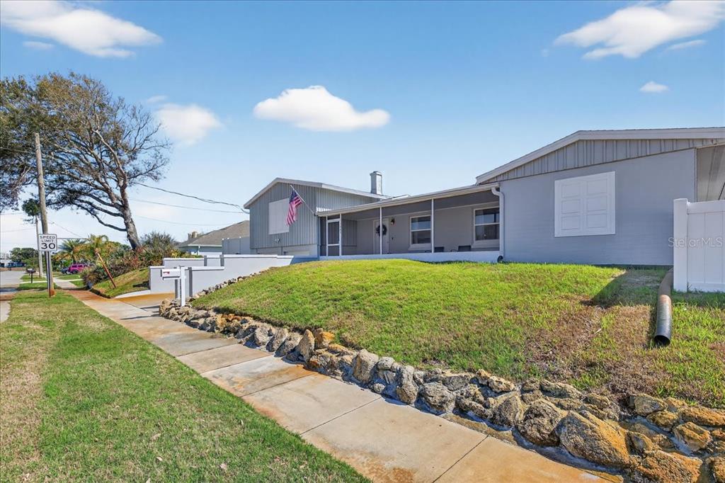 A single-story house with gray siding, a covered porch, and a stone retaining wall — 1600 N OLEANDER AVENUE, DAYTONA BEACH, FL