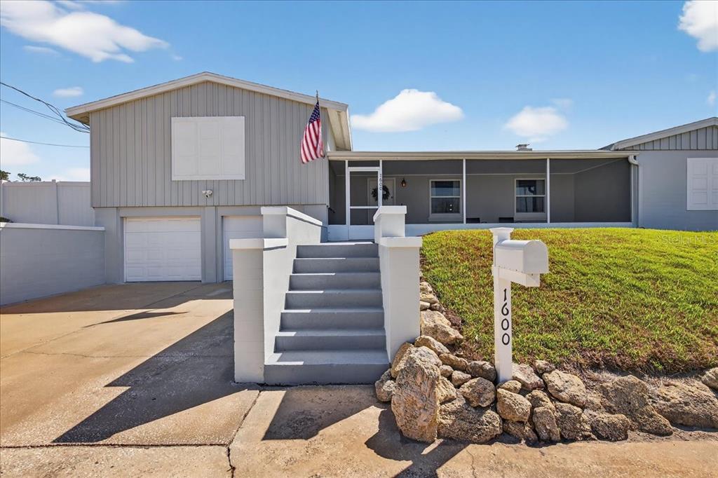 A split-level house with a gray exterior, a front staircase, and a screened-in porch — 1600 N OLEANDER AVENUE, DAYTONA BEACH, FL