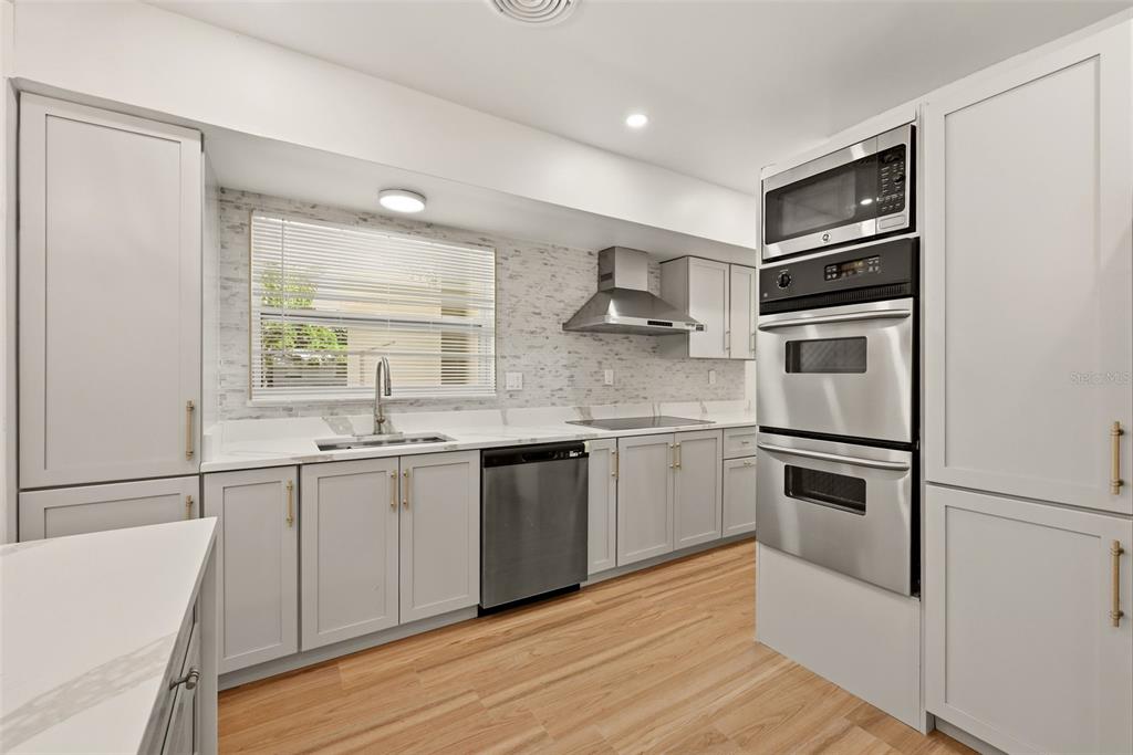 A kitchen with white marble-topped island and light gray cabinets opens to a living area — 2440 66TH AVENUE S, ST PETERSBURG, FL