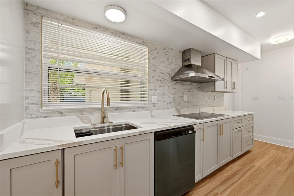 A modern kitchen features a large white marble island, gray cabinets, and stainless steel appliances — 2440 66TH AVENUE S, ST PETERSBURG, FL