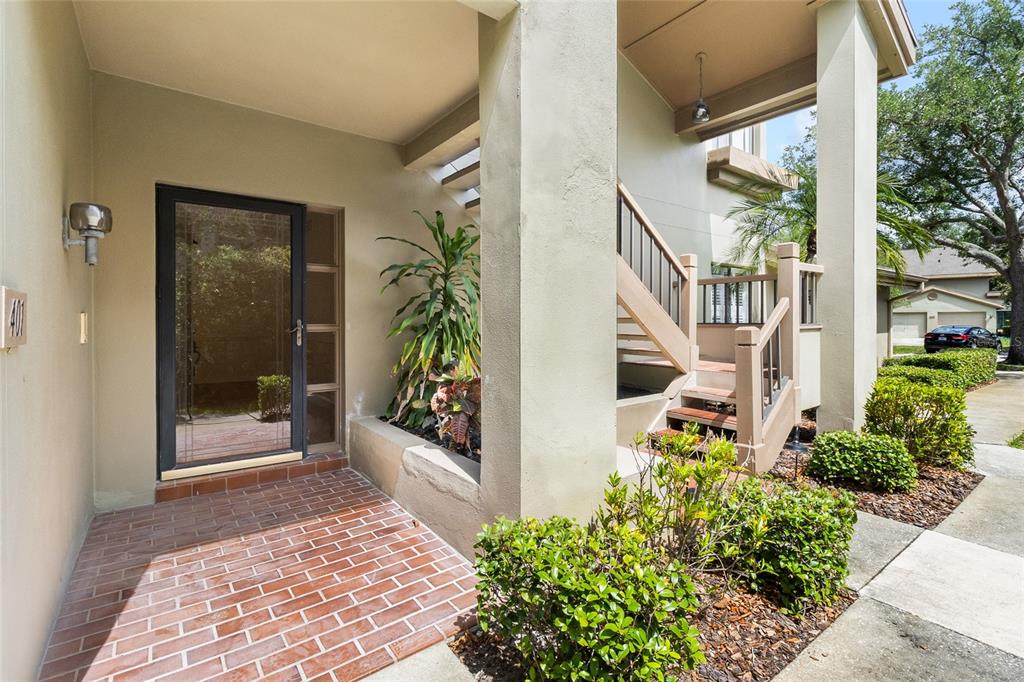 A ground-level entryway features a brick porch, a glass storm door, and an outdoor staircase — 3016 LANDMARK BOULEVARD UNIT 401, PALM HARBOR, FL
