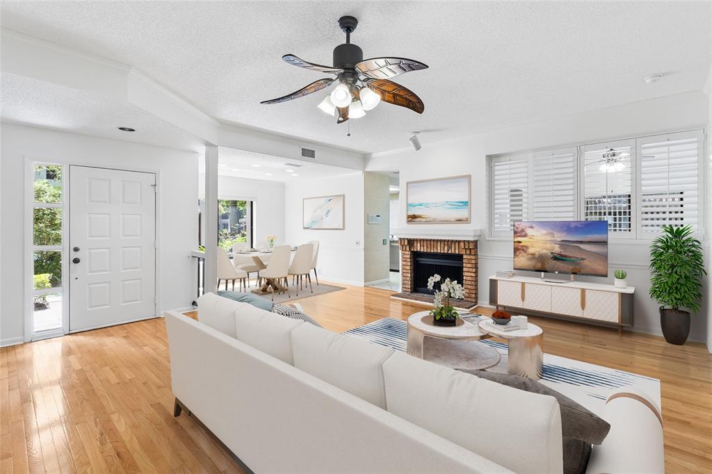 A living room with hardwood floors, a brick fireplace, and a palm-leaf ceiling fan — 3016 LANDMARK BOULEVARD UNIT 401, PALM HARBOR, FL