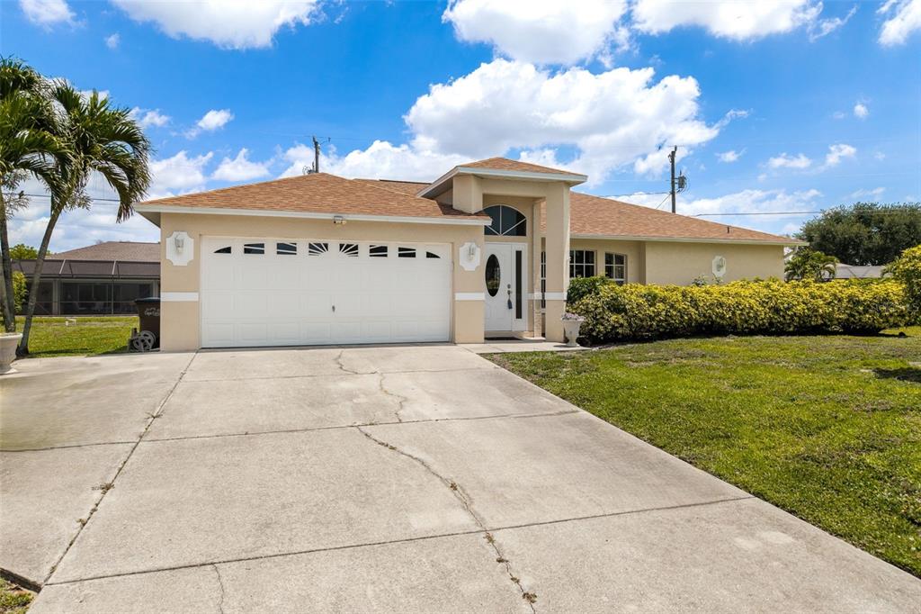 A single-story house with a white garage door, beige stucco exterior, and a concrete driveway — 1127 SW 29TH STREET, CAPE CORAL, FL