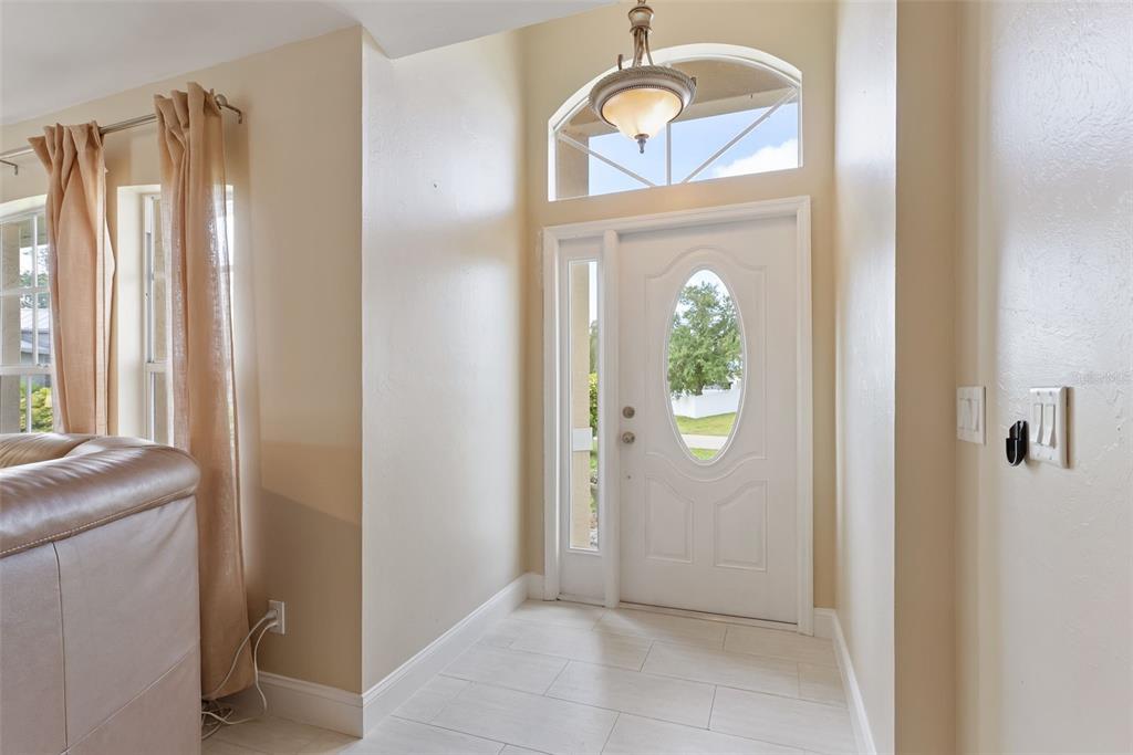 An entryway features a white front door with an oval window, tile flooring, and chandelier — 1127 SW 29TH STREET, CAPE CORAL, FL