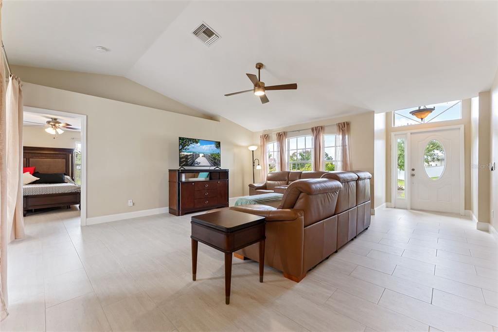 A living room with light tile floors, a brown leather sofa, and a vaulted ceiling — 1127 SW 29TH STREET, CAPE CORAL, FL