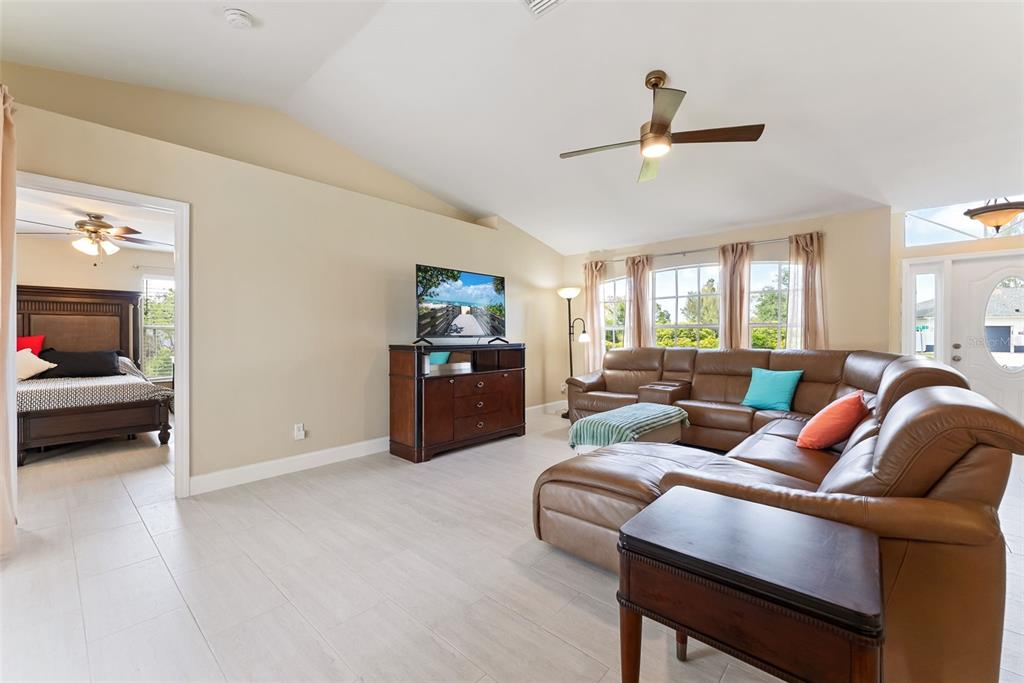 A living room with a brown leather sectional, television console, and tile flooring — 1127 SW 29TH STREET, CAPE CORAL, FL