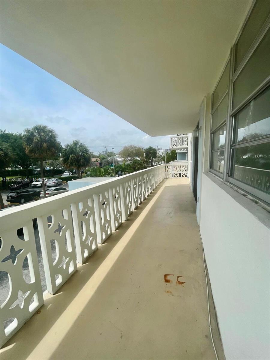 An outdoor balcony with a white decorative railing overlooks a parking lot and palm trees — 13155 Ixora Ct # 201, North Miami FL 33181, NORTH MIAMI, FL