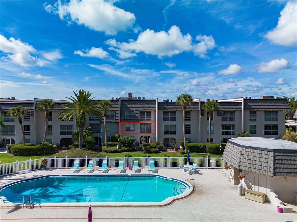 An exterior view of a multi-story apartment building overlooking a swimming pool — 712 CORDOVA GREENS UNIT 712, SEMINOLE, FL