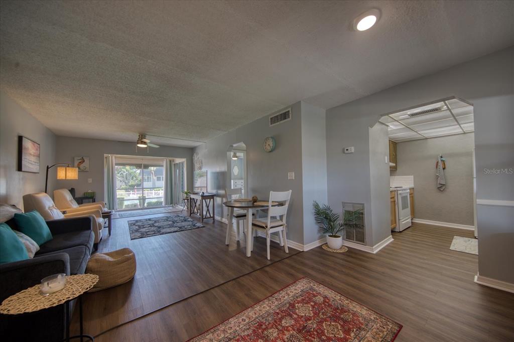 An open-concept living and dining area features wood-look flooring, a kitchen pass-through, and sliding doors — 712 CORDOVA GREENS UNIT 712, SEMINOLE, FL