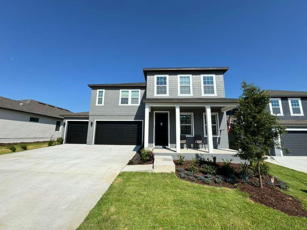 A two-story gray house with a three-car garage and a covered front porch — 2193 GOLD DUST DRIVE, MINNEOLA, FL