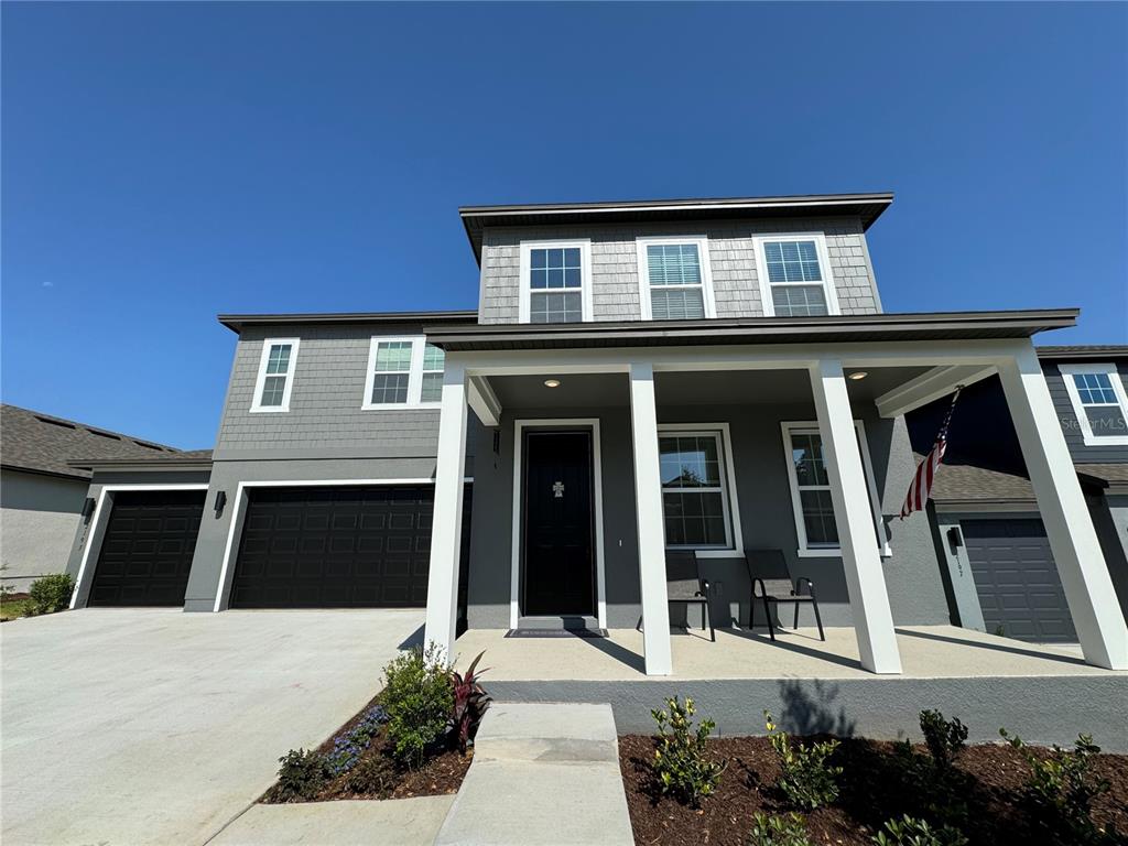 A two-story gray house features a covered front porch, a two-car garage, and shingle siding — 2193 GOLD DUST DRIVE, MINNEOLA, FL
