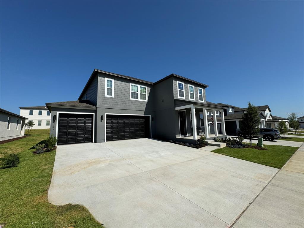 A two-story gray house with a three-car garage and a covered front porch — 2193 GOLD DUST DRIVE, MINNEOLA, FL