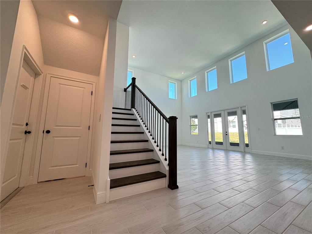 A bright living area features a staircase with dark wood treads and white tile flooring — 2193 GOLD DUST DRIVE, MINNEOLA, FL