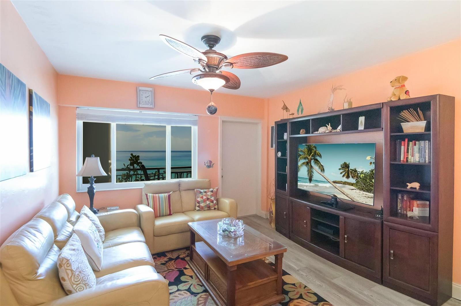 A living room with peach walls, a ceiling fan, leather sofa, and a large entertainment center — 1815 N Surf Road # 403, Hollywood FL 33019, HOLLYWOOD, FL