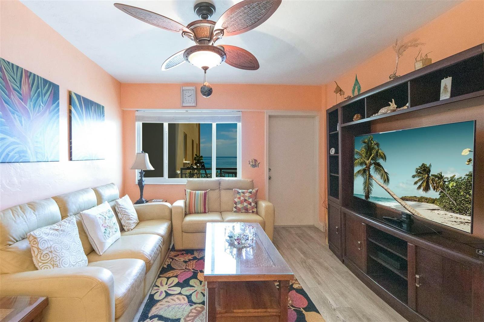 A living room features a beige sofa, a glass coffee table, and a large media console — 1815 N Surf Road # 403, Hollywood FL 33019, HOLLYWOOD, FL