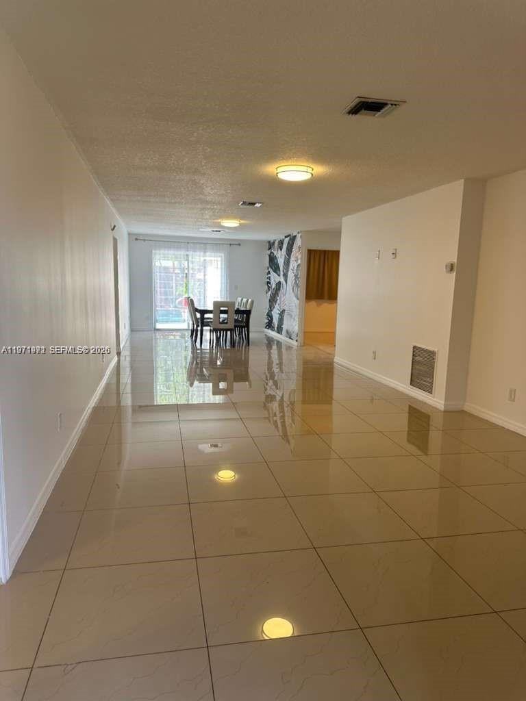A long, open-concept living and dining area features glossy tile flooring and recessed lighting — 208 SW 2nd Ave, Hallandale Beach FL 33009, HALLANDALE BEACH, FL