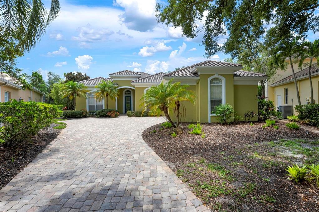 A single-story house with a paved driveway, palm trees, and a tan stucco exterior — 29 SAINT JOHN BOULEVARD UNIT 5, ENGLEWOOD, FL