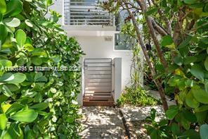 A gated entrance leads to a white building exterior framed by lush green hedges — 1600 Michigan Ave # 7, Miami Beach FL 33139, MIAMI BEACH, FL