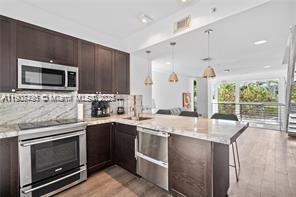 A kitchen features dark wood cabinets, stainless steel appliances, and a marble-topped island — 1600 Michigan Ave # 7, Miami Beach FL 33139, MIAMI BEACH, FL