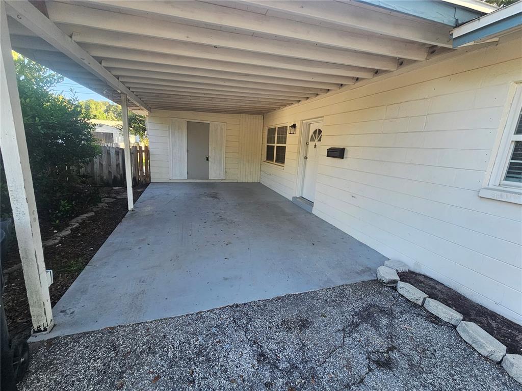 A concrete carport with a white exterior wall and a front door — 8068 23RD AVENUE N, ST PETERSBURG, FL