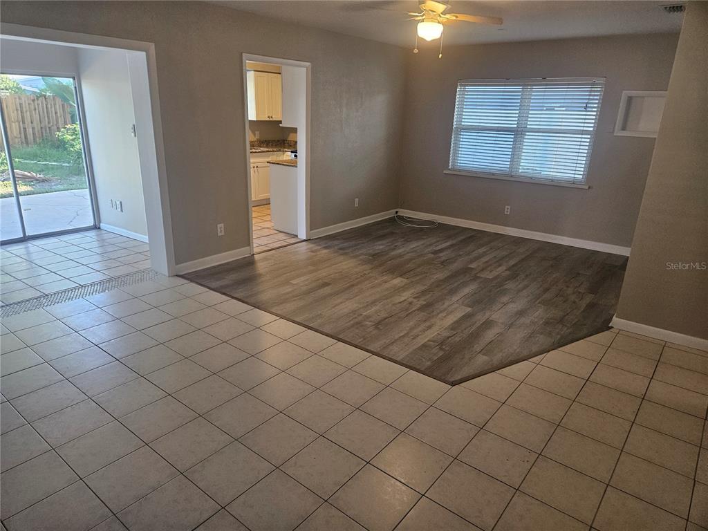 A living room features a mix of light-colored floor tiles and dark wood-look flooring — 8068 23RD AVENUE N, ST PETERSBURG, FL