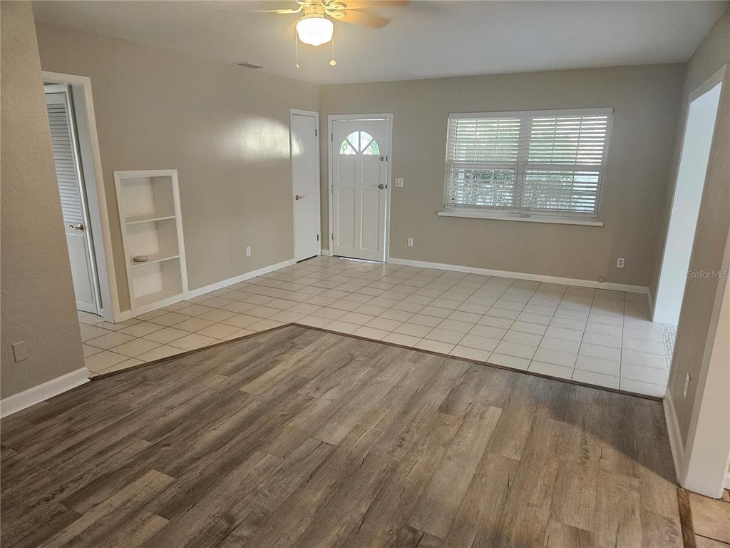 A living room features a mix of wood-look laminate and light-colored tile flooring — 8068 23RD AVENUE N, ST PETERSBURG, FL