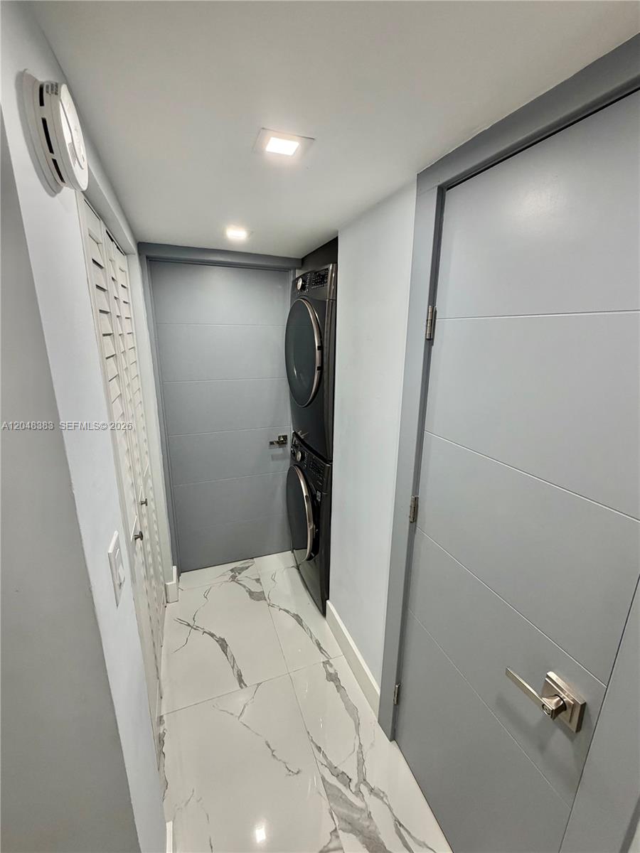 A laundry closet features a stacked washer and dryer set on a marble-tiled floor — 1100 W 35th St # 4, Hialeah FL 33012, HIALEAH, FL