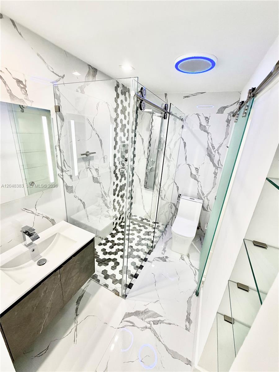 A modern bathroom features marble-patterned walls, a glass-enclosed shower, and a floating vanity — 1100 W 35th St # 4, Hialeah FL 33012, HIALEAH, FL