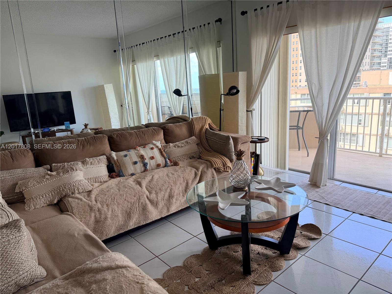 A living room features a brown sectional sofa, glass coffee table, and balcony access — 1950 S Ocean Dr # 4B, Hallandale Beach FL 33009, HALLANDALE BEACH, FL